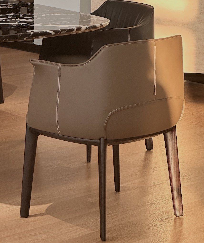 A taupe leather dining chair with contrast stitching and dark timber legs