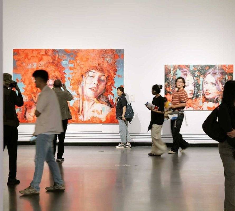 Visitors walking past Dreamers and other paintings by Silvio Porzionato at the Guanghui Art Museum in Chengdu