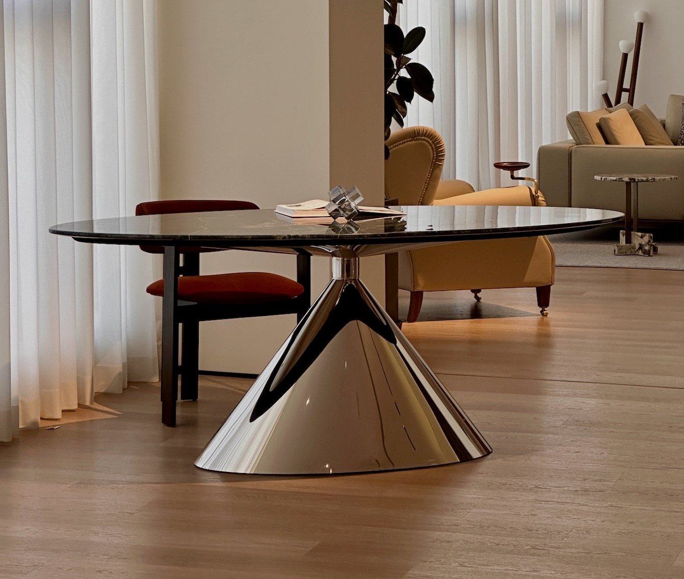 An oval marble dining table on a polished steel cone base