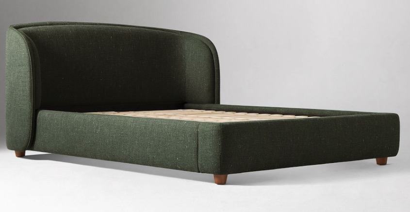 The same green upholstered bed without bedding, showing its wrapped side rails, slatted base and low timber feet