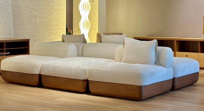 A low modular sofa in white textured upholstery on solid walnut bases