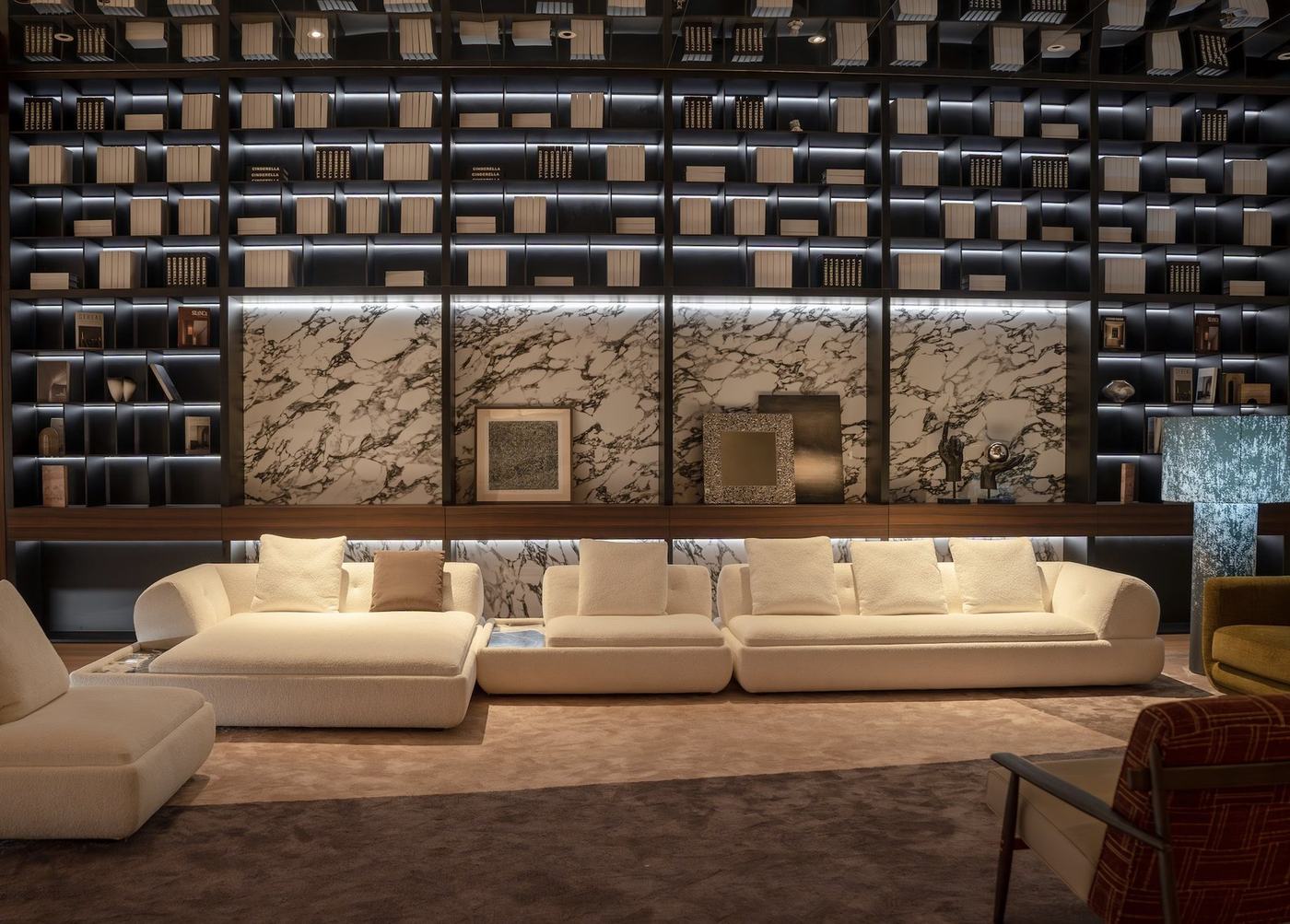 An ivory bouclé sectional in front of a lit library wall with marble panels